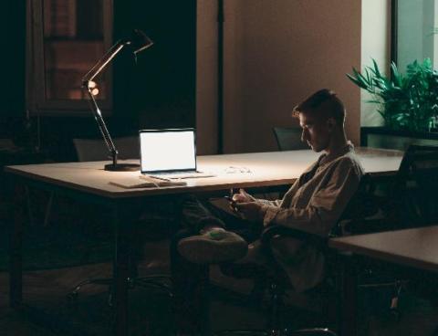 Man next to his computer on his smartphone