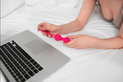 Model holding a sex toy in front of her screen